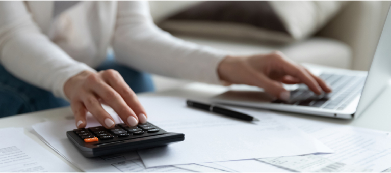Woman sat at desk, planning with a laptop and calculator